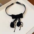 Primo piano di un elegante choker in tessuto nero con fiocco e nappine a tulipano - Solo Catena / Nero