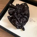 Primo piano di un fermaglio per capelli a fiori con volant a pois bianchi e neri con twist - Clip a Torsione / Polka Dot Nero