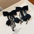 Dettaglio di orecchini a fiocco in tessuto nero con nappe di perline - Earrings Only / Nero