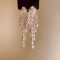 Detailed macro view of sparkling gold plated zircon tassel earrings with brilliant shine - Gold