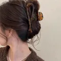 Detail view of stylish tortoise shell wavy hair claw clip used for a chic back bun - Cross Claw Clip / Coffee-Crossed
