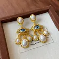Detailed shot of vintage gold earrings with evil eye design and faux pearl tassels - Silver Post-Gold Style (WE1135) / Gold
