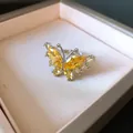 Vista macro di un elegante anello a farfalla in argento con pietre di zircone giallo - Design a Farfalla / Argento-Giallo