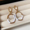Detail view of gold-tone oval drop earrings with white enamel finish in a box - Silver Pin-Gold-White