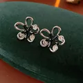 Elegant black enamel flower stud earrings with clear crystals on a green velvet box - 109 Silver Needles - Silver