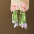 Detailansicht handgefertigter Perlenohrringe mit rosa Blüten und grünen Quasten im Blumendesign - Stil 7 / Rosa/Grün