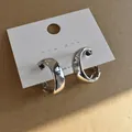 Detailed view of chunky silver-colored geometric hoop earrings on a display card. - Silver
