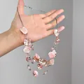 Detail van een meerlaagse ketting met roze schelpen voor een strandvakantie-look. - Roze