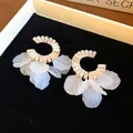 Dettaglio di orecchini a cerchio in zirconia con pendenti a petali bianchi satinati - Oro-Bianco