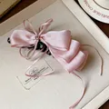 Detailed view of pink satin ribbon bow banana hair clip on a beige textured tray - Bow Banana Clip / Single Piece / Pink