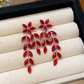 Close-up of red glass flower and leaf tassel earrings on a luxury cream jewelry tray. - Silver Earring Post Style / Red