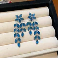 Detailed close-up view of elegant blue glass flower and leaf tassel dangle earrings - Silver Earring Post Style / Blue