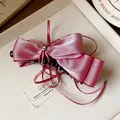 Detailed view of an elegant pink satin bow hair clip with a tiny star charm and long ribbons - Bow Banana Clip / Single Piece / Red