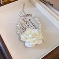 Detailed view of the elegant white fabric rose on a pearl beaded choker necklace. - Bracelet / White