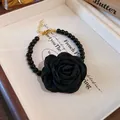Detailed view of an elegant black fabric rose with a black beaded choker necklace. - Bracelet / Black