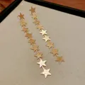 Primer plano detallado de los pendientes de borla con estrellas doradas y textura metálica - Color Dorado (Pin de Acero)