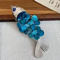 Macro view of a metallic fish charm featuring blue iridescent scales and a nazar eye bead. - Fish Shaped Duckbill Clip / 1 Piece / Silver Blue Fish Right