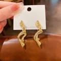 Élégantes boucles d'oreilles pendantes vagues torsadées dorées sur leur carte. - Style Torsion Rayé (HE10333) / Pack de 1 paire / Torsion Rayée
