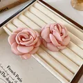 Elegant handmade pink fabric camellia flower accessory displayed on a cream jewelry tray - Earrings / Pink