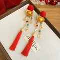 Close-up of festive red hair clips with gold tassels and ingot charms for Chinese New Year - Duckbill Hair Clips / One Pair / Red Flocking Ingot Lion Dance
