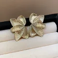 Detailed close-up of elegant gold floral petal textured stud earrings in a box - Gold
