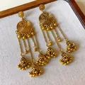 Close-up of vintage ethnic gold-colored tassel earrings with intricate circular patterns. - Gold