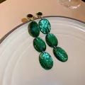 Close-up of elegant emerald green oval faceted drop earrings on a ceramic plate - Gemstone Long Style (2#)