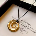 Dettaglio di una collana con ciondolo a spirale dorata minimalista in un portagioie premium - Stile Cerchio a Spirale (HN7355) / Oro