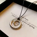 Primo piano di un ciondolo a spirale in metallo argento su cordino nero - Stile Cerchio a Spirale (HN7355) / Argento