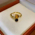 Close-up of 18k gold plated ring featuring tiger eye and dark spherical gemstones - Double Stone Cross Design (HR2927) / Gold Brown