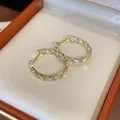 Elegante Nahaufnahme von vergoldeten Zirkonia-Creolen in einer orangefarbenen Schachtel - Runde Ohrschnalle (HE30368) / Gold