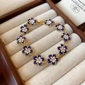 Dettaglio ravvicinato di un braccialetto a fiori in smalto blu Klein con strass lucidi - Oro-Blu Klein