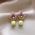 Close-up detail of purple enamel flower earrings with pearls on silk fabric - Gold-Purple-Green
