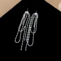 Primo piano dettagliato di orecchini a nappa in argento con un brillante zircone rotondo. - Stile Nappine a Catena di Perle Argento con Zirconia Rotonda