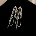 Dettaglio macro di eleganti orecchini a nappa dorati con zirconi tondi scintillanti - Stile Nappine a Catena di Perle Oro con Zirconia Rotonda