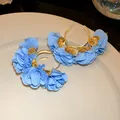 Detailed macro view of sky blue chiffon flower C-shape hoop earrings on a white ceramic plate - C-Shape Floral Style (HE30814) / Blue