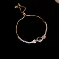 Detailansicht eines eleganten Goldarmbandes mit grünem Zirkon und klaren Kristallen - Ovale Anhänger Armband / Gold-Blau