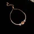 Detailansicht eines Goldarmbandes mit funkelndem ovalen Zirkon und verstellbarem Verschluss - Ovale Anhänger Armband / Goldbraun