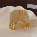 Vista detallada de un brazalete abierto de lujo envuelto en hilo de oro para mujer. - Dorado