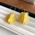 Detailed view of yellow hollow flower ear hooks with delicate gauze petals and gold finish - Flower Style (HE25162) / Yellow