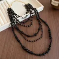 Detail view of a multi-layer retro necklace with black acrylic beads and gold chain - Multilayer Beaded Style / Black