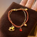 Détail d'un bracelet double épaisseur plaqué or 18k avec cordon rouge et breloque cheval à bascule. - Style Double Couche Cheval et Cœur (6#)