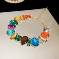 Close-up of a colorful rhinestone necklace with teardrop and square gems in gold-tone setting. - Gold Base Multi-Shape Colorful Stones