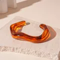 Close-up detail of an irregular wavy amber acrylic cuff bracelet with marble texture - 83# Bangle