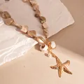 Vista dettagliata della collana di conchiglie con ciondolo a stella marina dorata su sfondo - Collana / Oro
