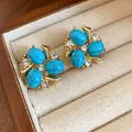Primo piano di raffinati orecchini vintage dorati con pietre turchesi e zirconi - Perno in argento-Blu
