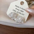 Detailed macro view of silver-plated flower clip-on earrings featuring elegant central pearls - Clip-On Earrings / One Pair / Silver