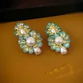 Gros plan de boucles d'oreilles fleurs avec cristaux bleus et perles blanches - Style de Fleur en Strass Vert (HE14859)
