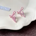 Dettaglio macro della finitura laccata rosa degli orecchini a fiocco minimalisti in argento - Orecchini a Bottone a Fiocco / Rosa