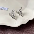 Dettaglio orecchini a lobo con fiocco d'argento con design minimalista in metallo liquido. - Orecchini a Bottone a Fiocco / Argento